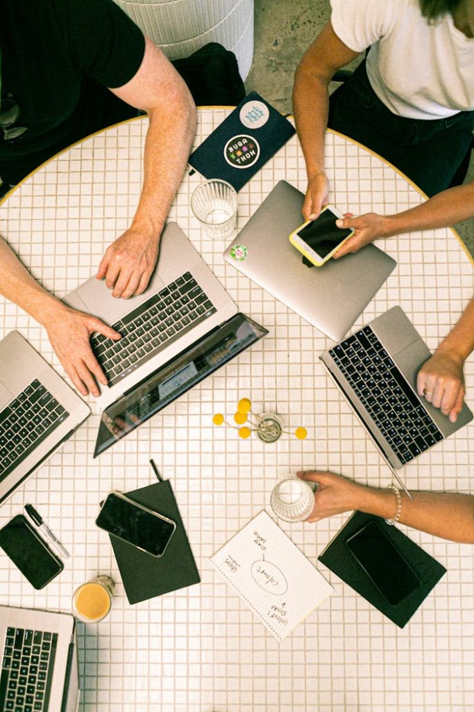 Mastering the First Impression: Your intriguing post title goes here Top view of a team collaborating with laptops, phones, and notes in a modern office.